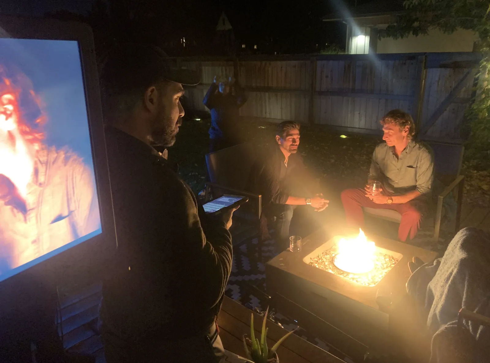 Night exterior fire pit scene with two actors and a crew member at the monitor