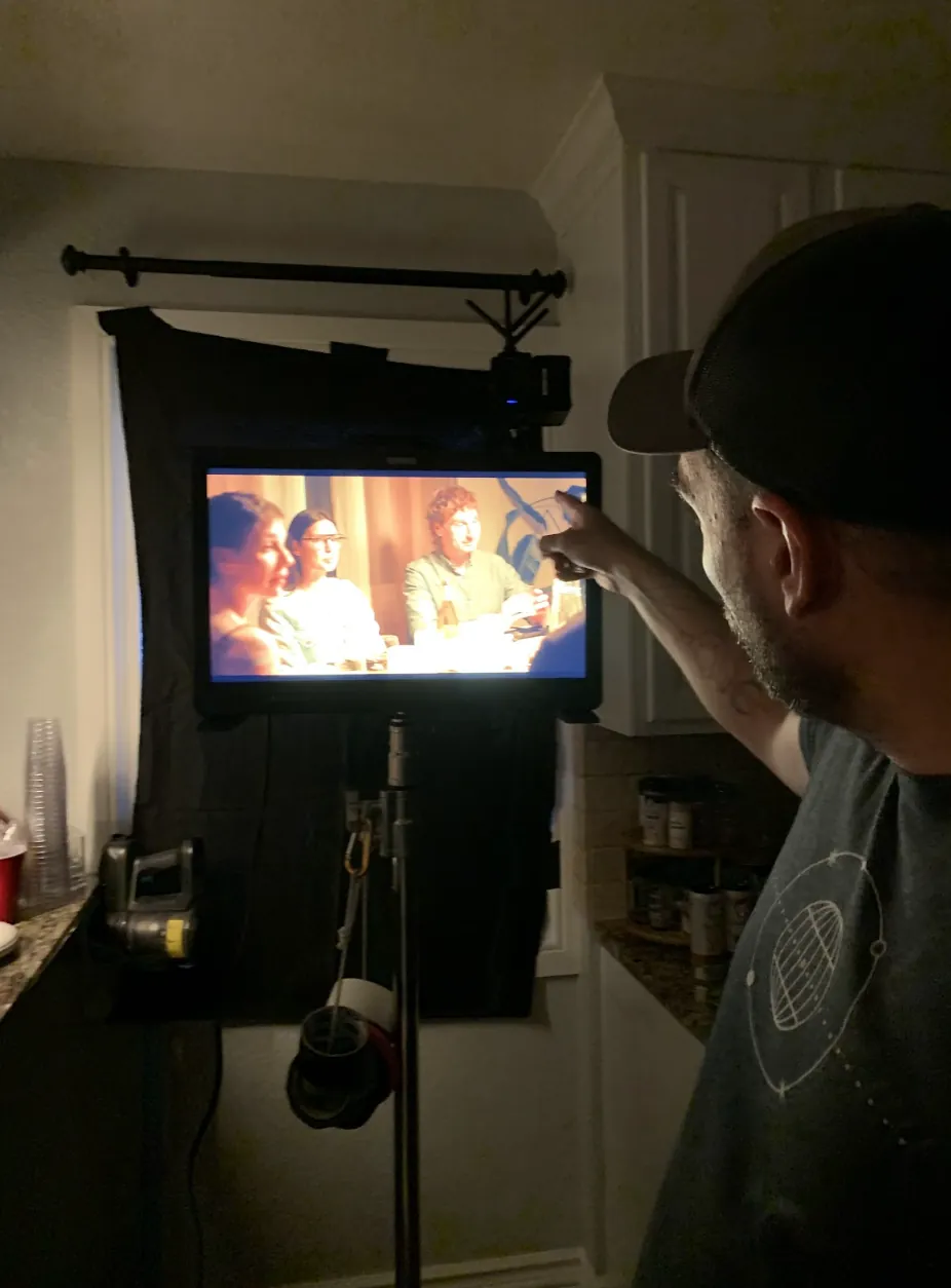 Director pointing at a monitor showing a dinner table scene